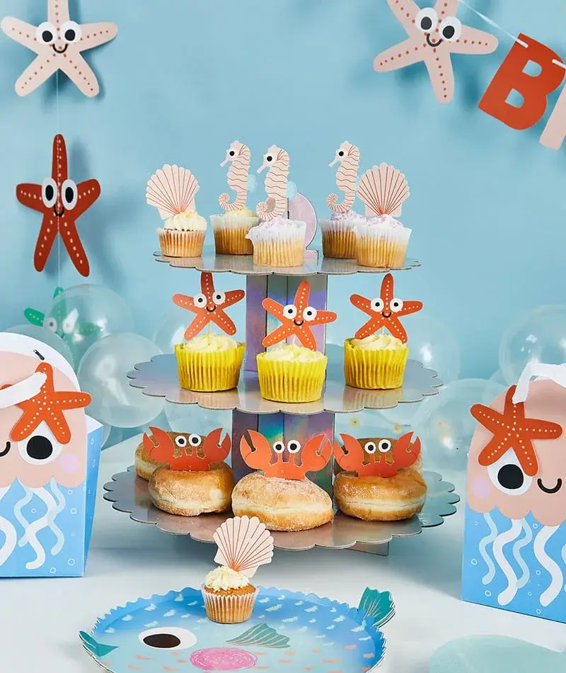 Under-the-sea party dessert stand with seahorse and starfish cupcake toppers, doughnuts, balloons, and ocean-themed party decorations. Under-the-sea party dessert stand with seahorse and starfish cupcake toppers, doughnuts, balloons, and ocean-themed party decorations.